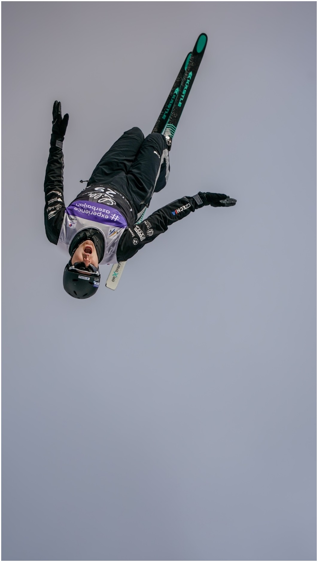 FIS aerials skier inverted against a gray sky