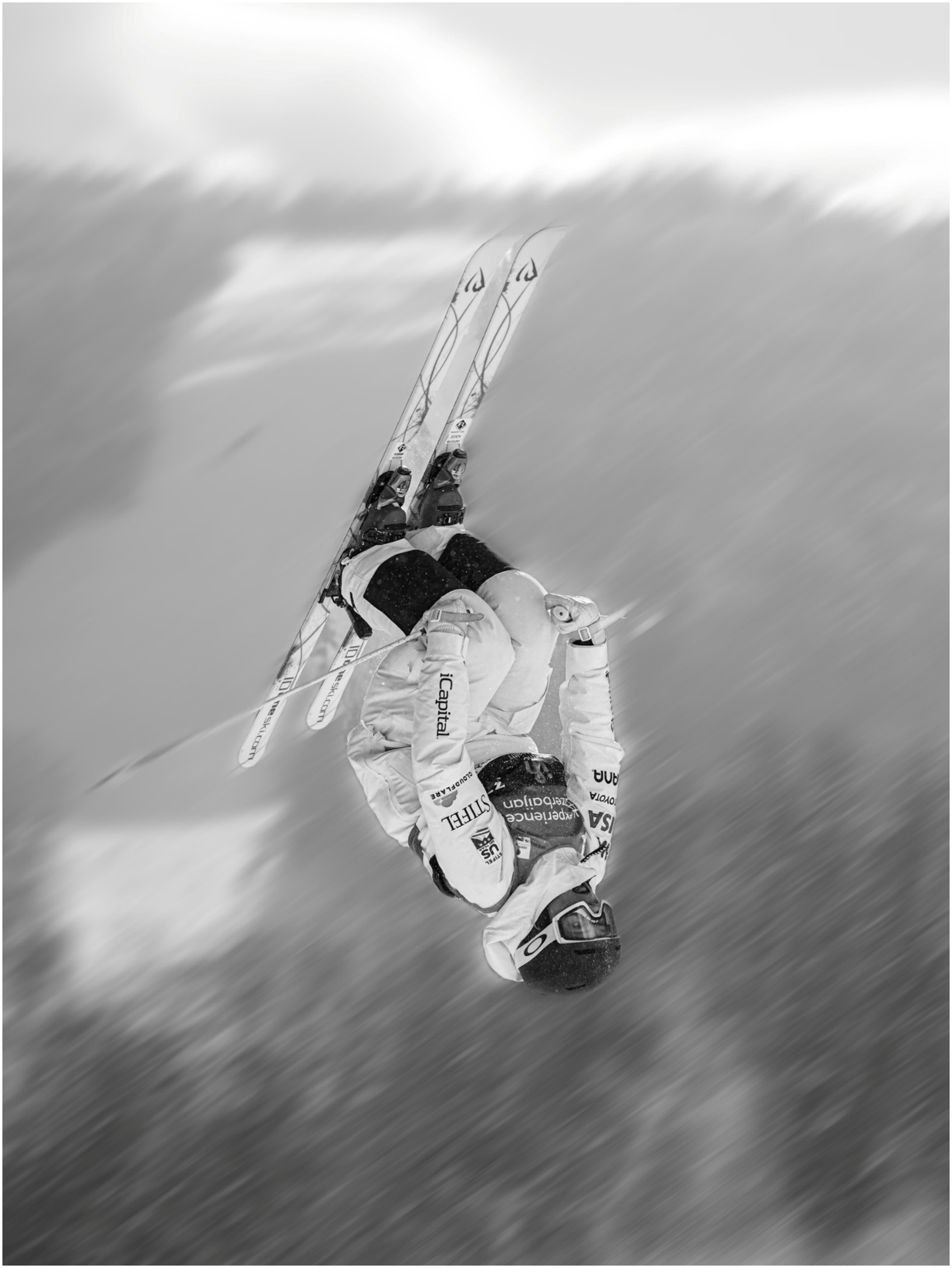 Black-and-white photograph of a freestyle moguls skier inverted in the air